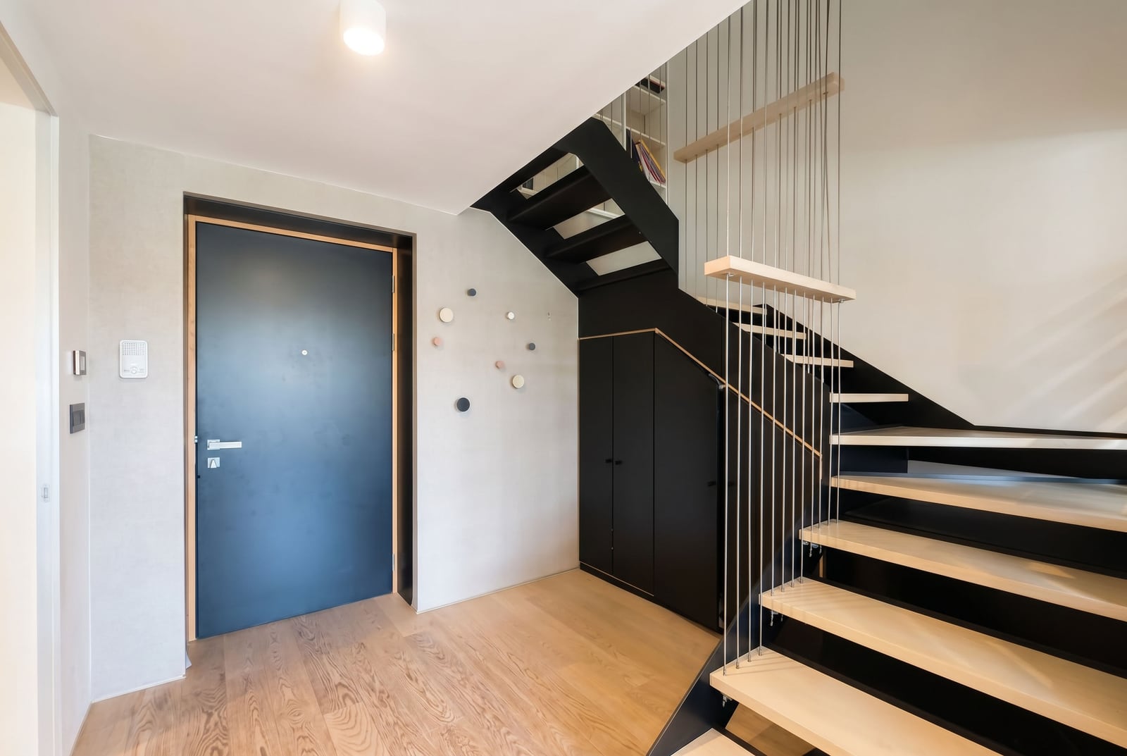 Modern hallway with a black staircase and wooden steps in an apartment, Budva, Montenegro.