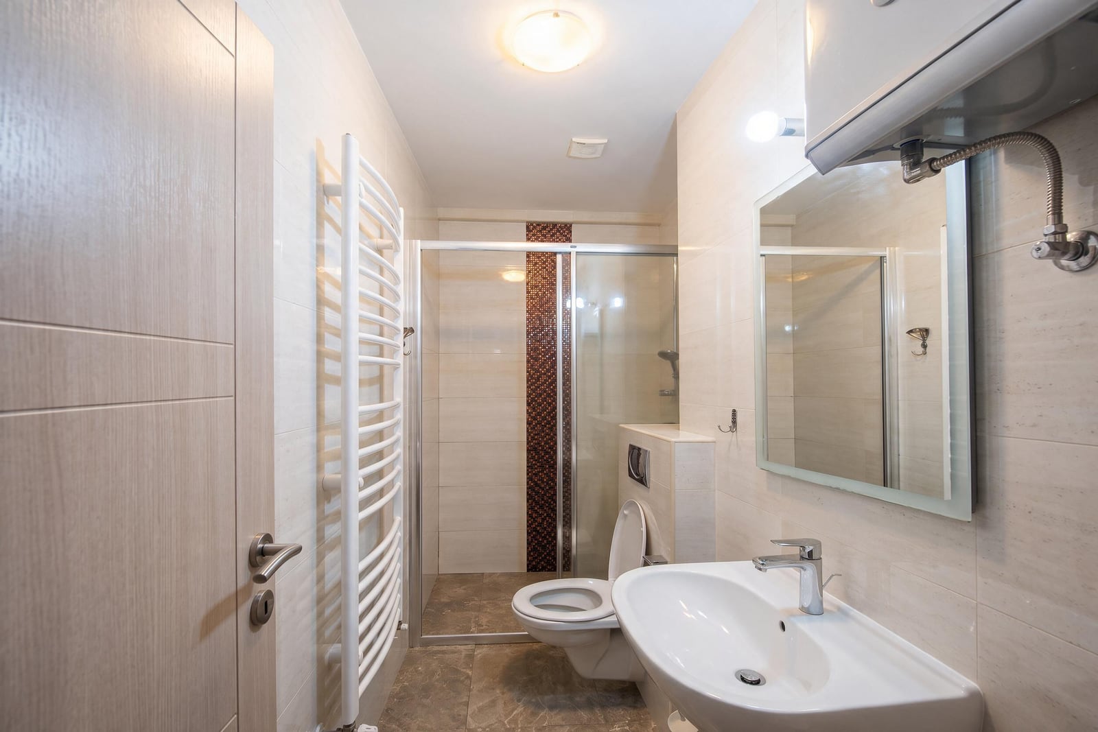 Modern bathroom with a shower cabin, sink, and towel warmer in an apartment in Bečići, Montenegro.