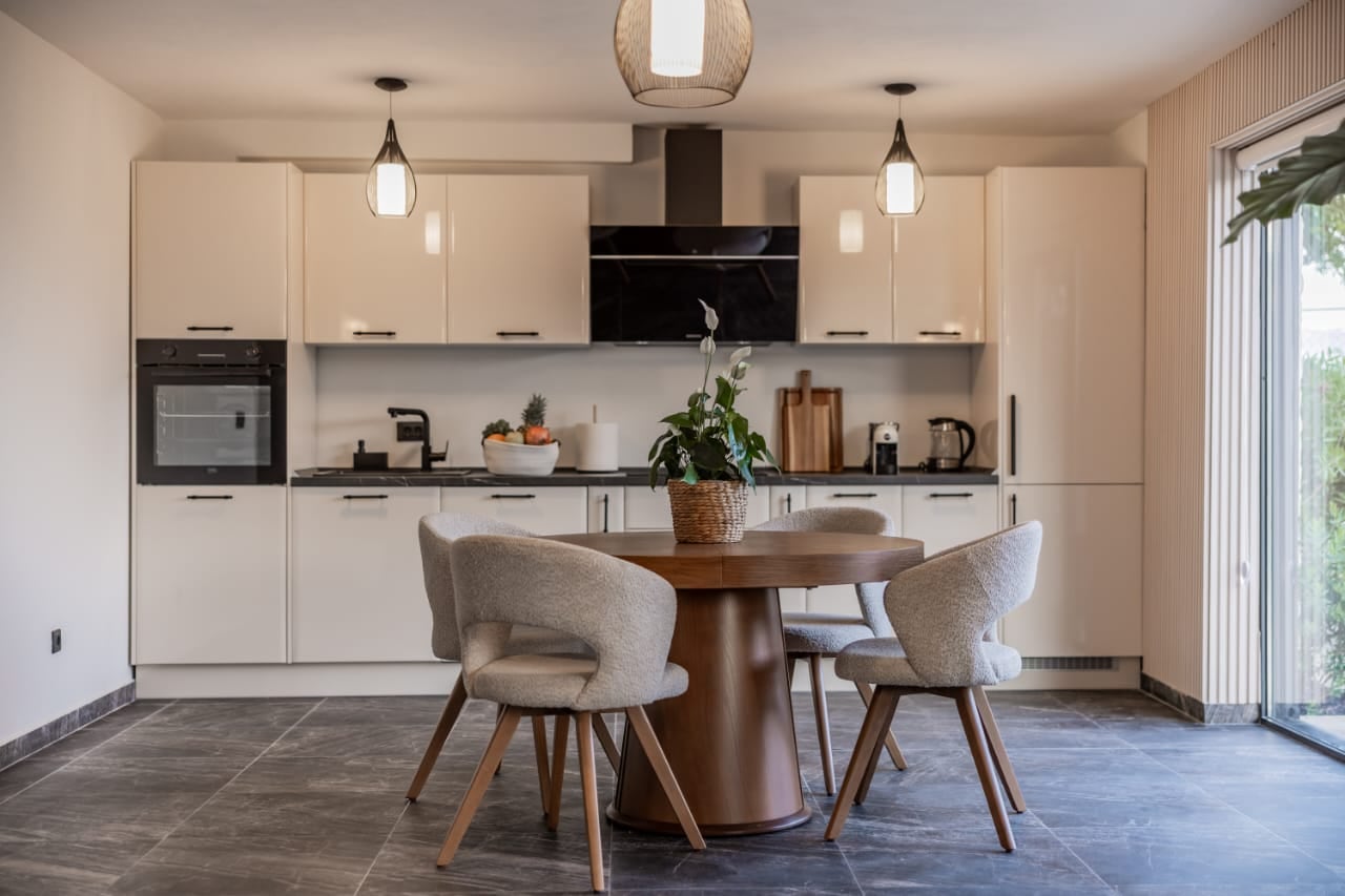 Modern kitchen-dining room in a villa in Budva, Montenegro: light-colored kitchen set, round dining table, and panoramic windows.