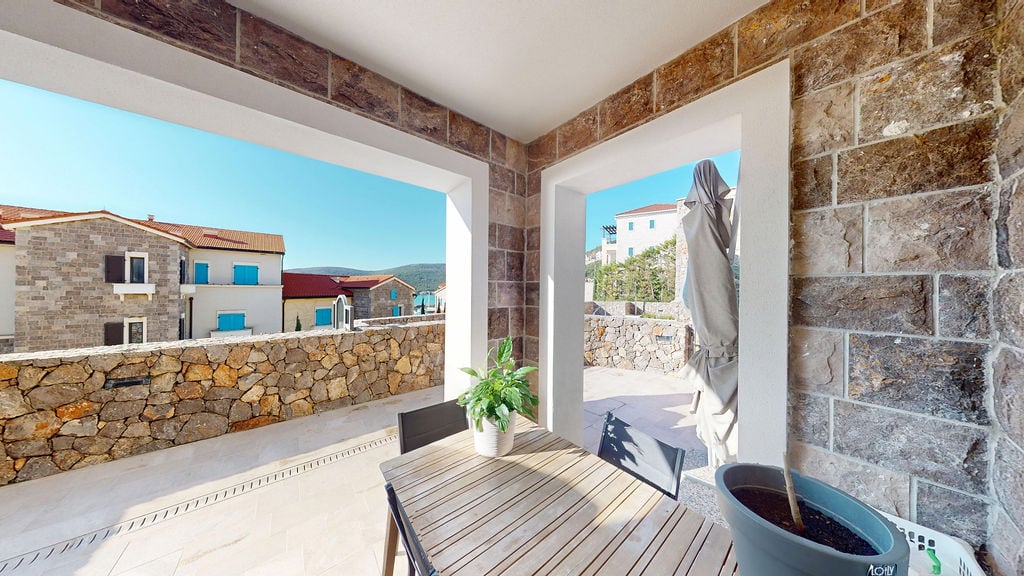 Spacious terrace with stone finish and dining table in the Luštica residential complex, Montenegro.