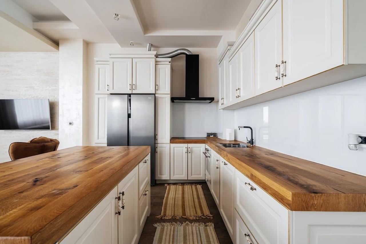 Modern kitchen with white fronts and a solid wood countertop in an apartment in Budva, Montenegro.