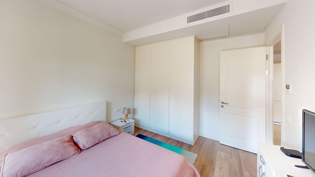 Bright bedroom with a double bed and built-in wardrobe in the Lustica Bay apartments, Montenegro.