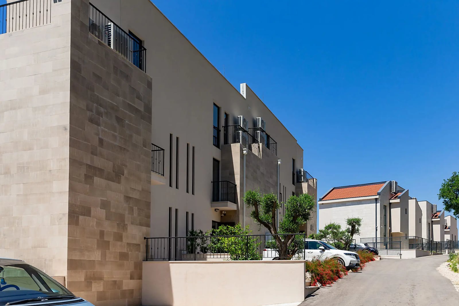 Modern villa with stone facade cladding in Reževići, Montenegro: view of the building, balconies, and surrounding grounds.