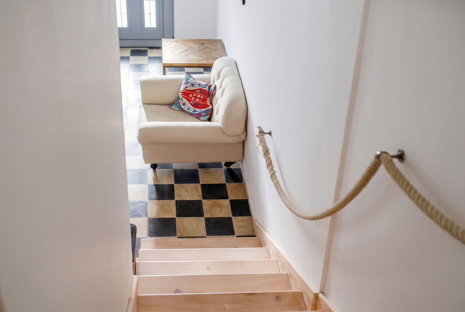 Bright living room in an apartment in Risan, Montenegro: wooden staircase, armchair, checkered floor, and rope railings.