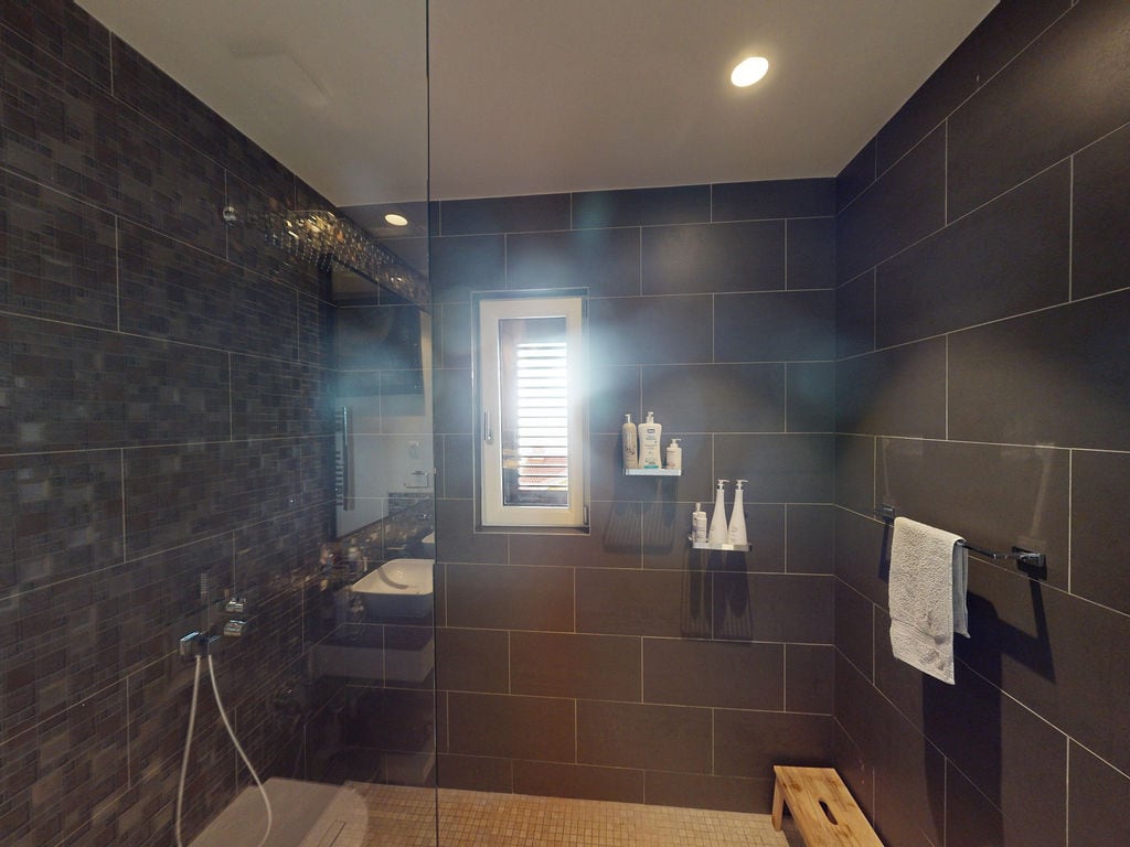 Modern bathroom with a shower cabin in a townhouse, Luštica, Montenegro: dark tiles and stylish finishes.