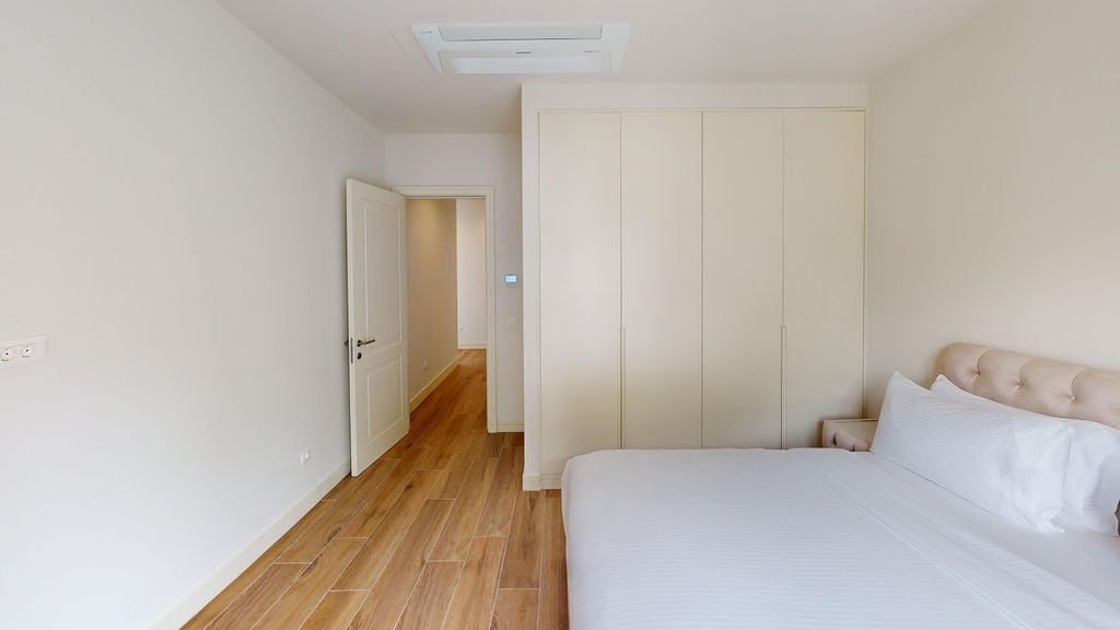 Bright bedroom in a Lustica Bay apartment, Montenegro: double bed, built-in wardrobe, and parquet flooring.