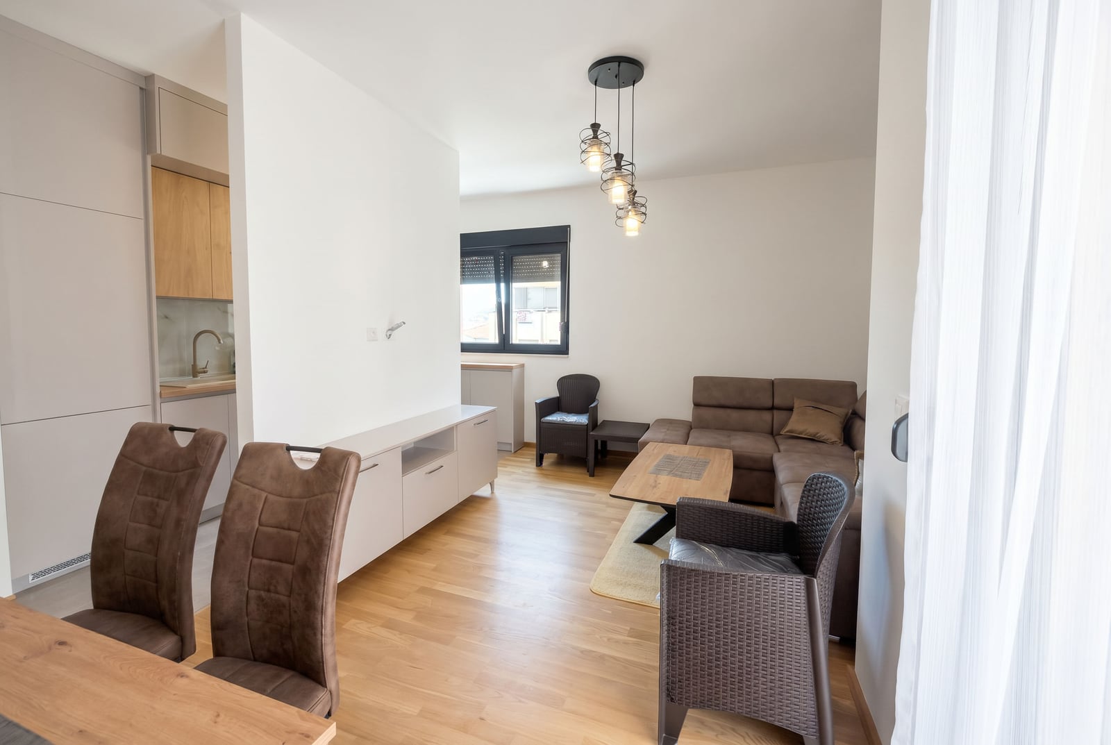 Modern living room with a kitchen in an apartment in Budva, Montenegro: corner sofa, dining area, and bright interior.