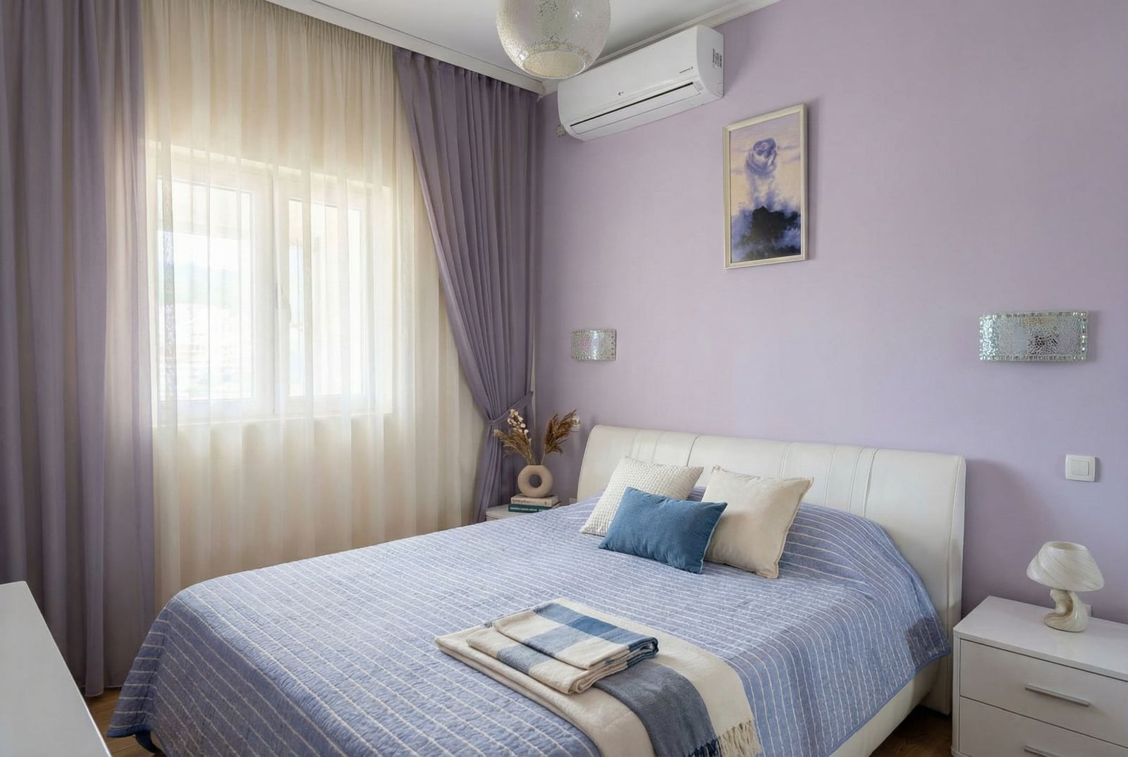 Cozy bedroom with a double bed in an apartment in Pržno, Montenegro: lilac walls, light furniture, and air conditioning.