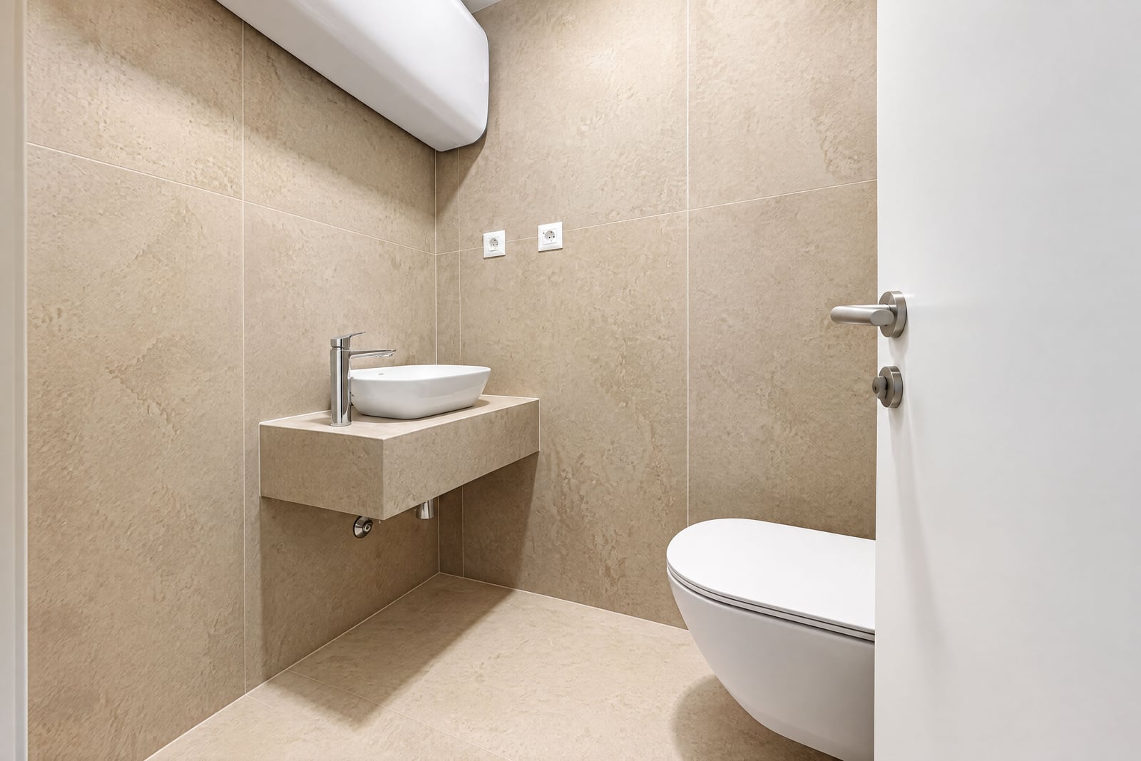 Modern bathroom with beige tiles, a wall-mounted toilet, and a vessel sink on a floating counter.