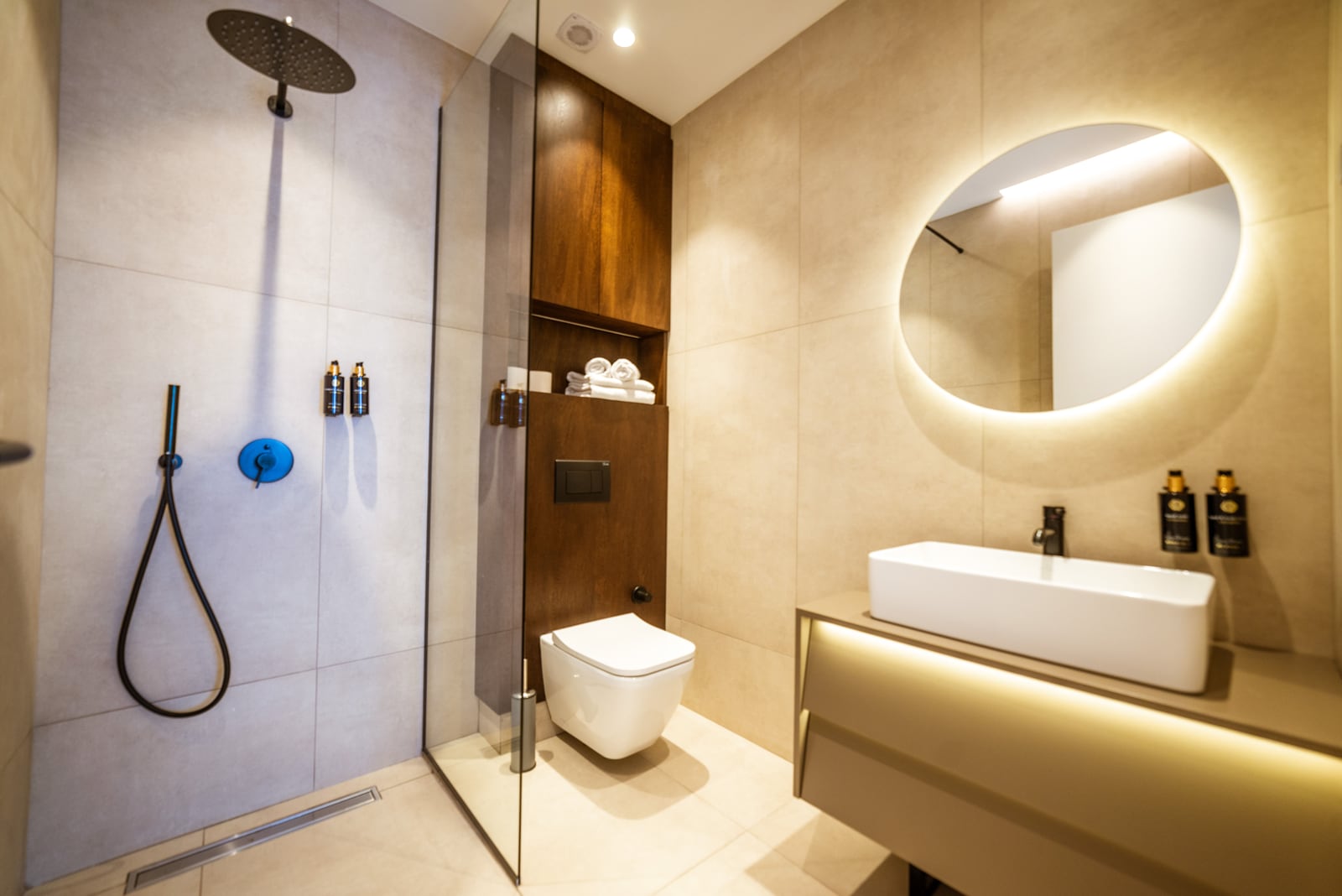 Modern bathroom in an apartment in Bečići, Montenegro: tropical rain shower, wall-hung toilet, and illuminated mirror.
