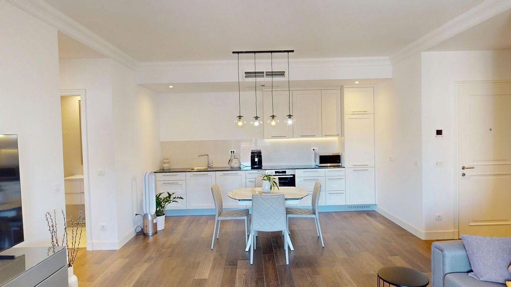 Modern kitchen-living room with a light-colored kitchen set and dining area in an apartment, Luštica, Montenegro.
