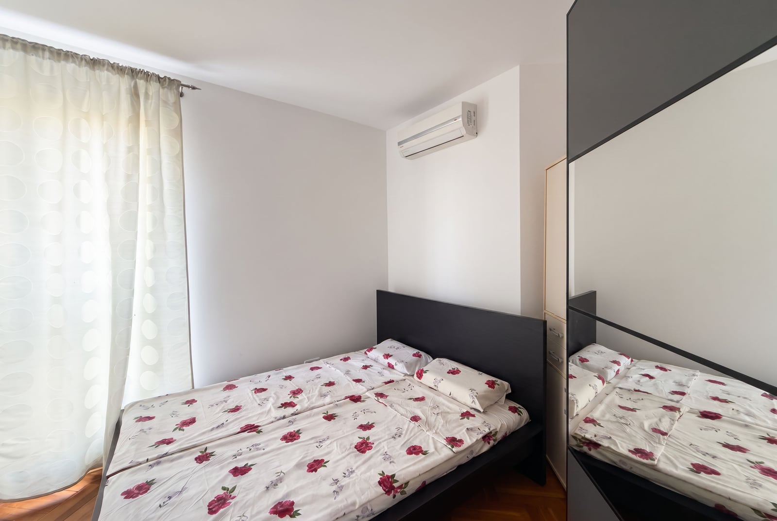 Bright bedroom with a double bed, air conditioning, and wardrobe in an apartment in Bečići, Montenegro.