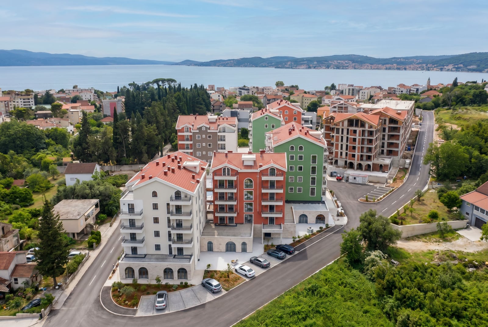 Residential complex with modern apartments in Tivat, Montenegro: aerial view of houses with red roofs by the sea.