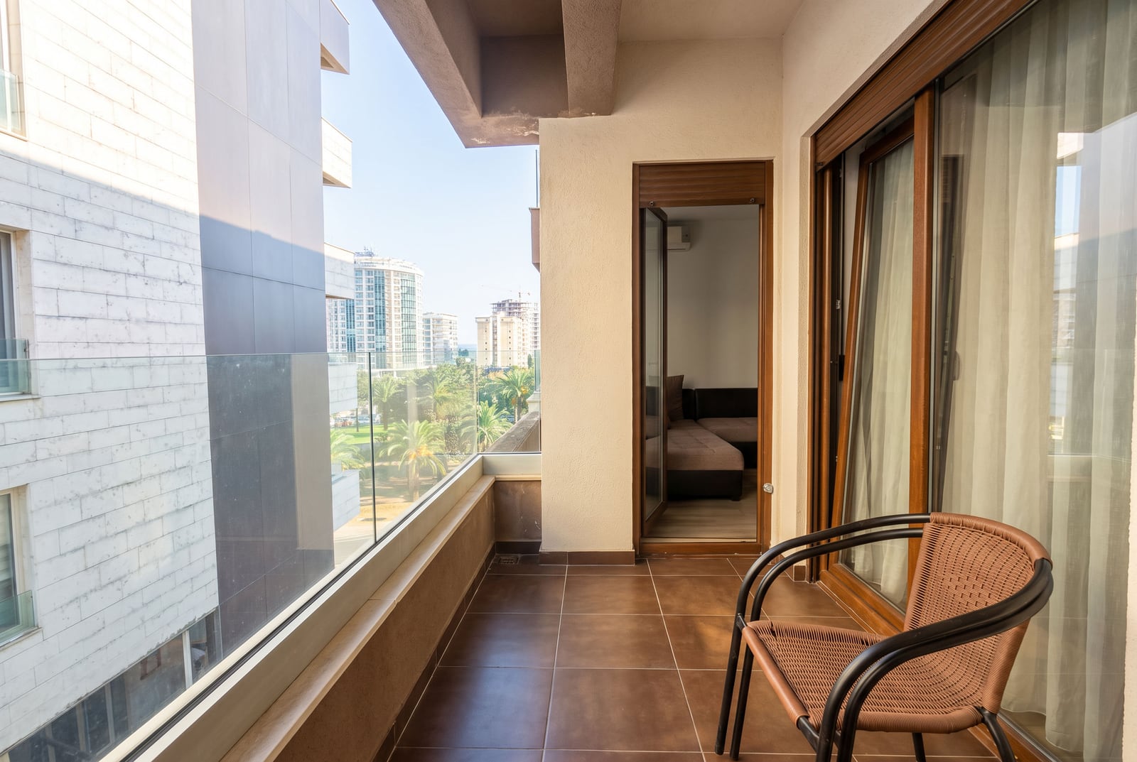 Spacious balcony with a wicker chair and panoramic view of the city in Budva, Montenegro