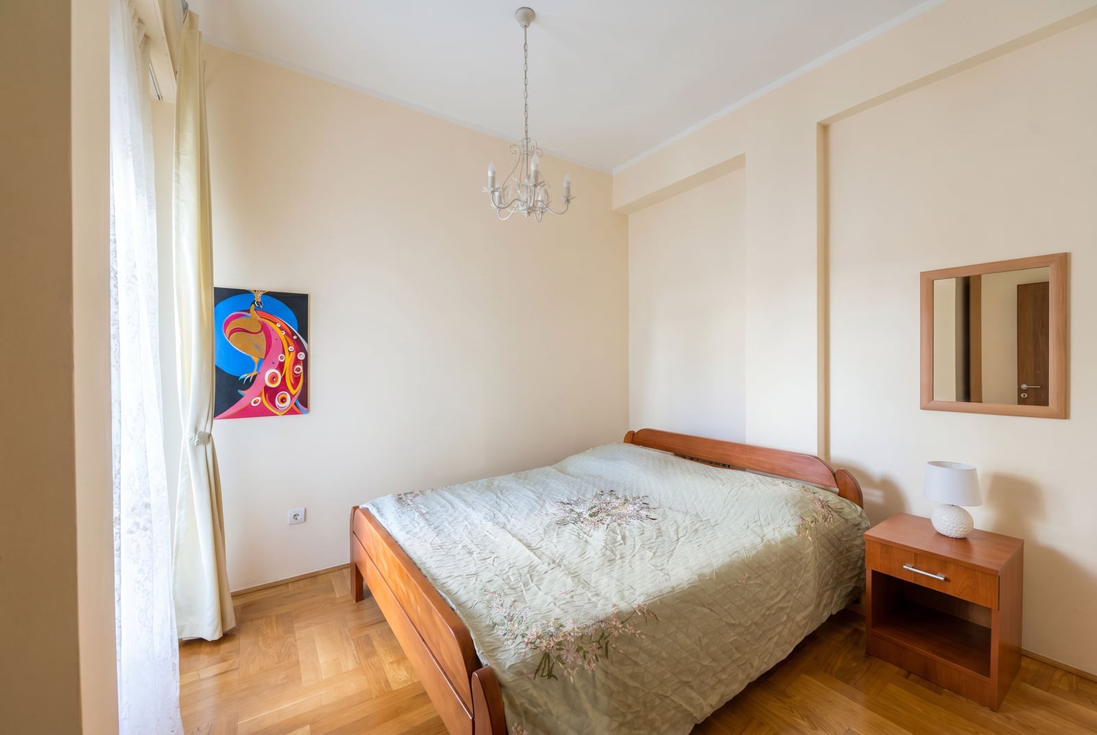 Bright bedroom with a double bed and parquet flooring in an apartment for sale in Budva, Montenegro.