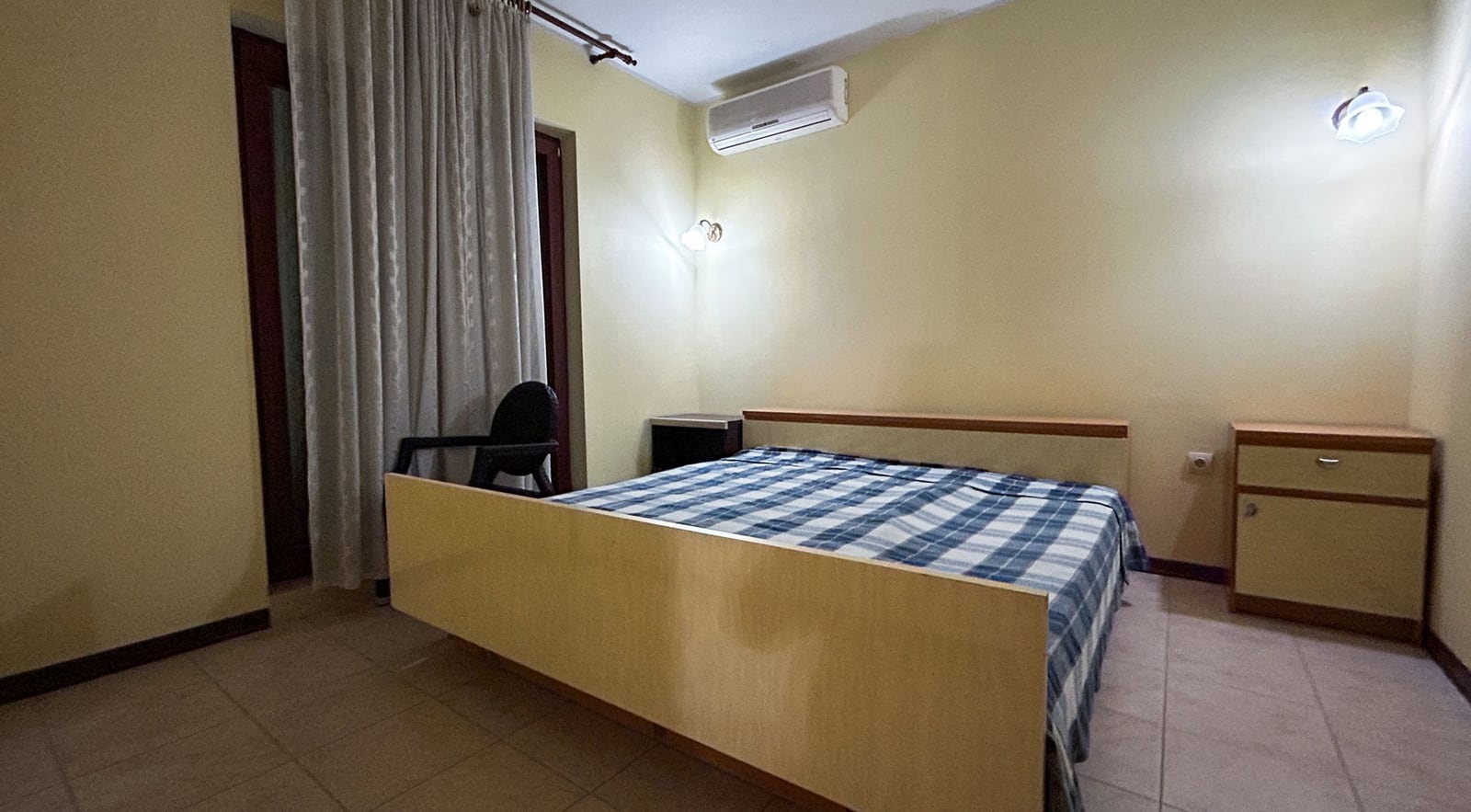 Bedroom with a double bed and air conditioning in a villa in Dobrota, Montenegro: light-colored furniture and access to the terrace.