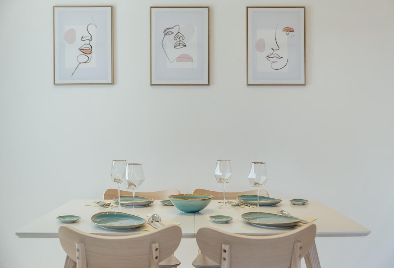 Set dining table in an apartment interior in Igalo, Montenegro: light-colored furniture and wall decor.