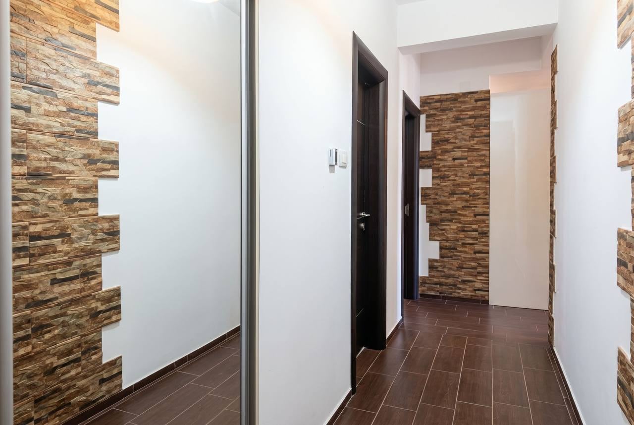 Modern hallway in an apartment in Budva, Montenegro: decorative stone finish, mirrored wardrobe, and tiled floor.