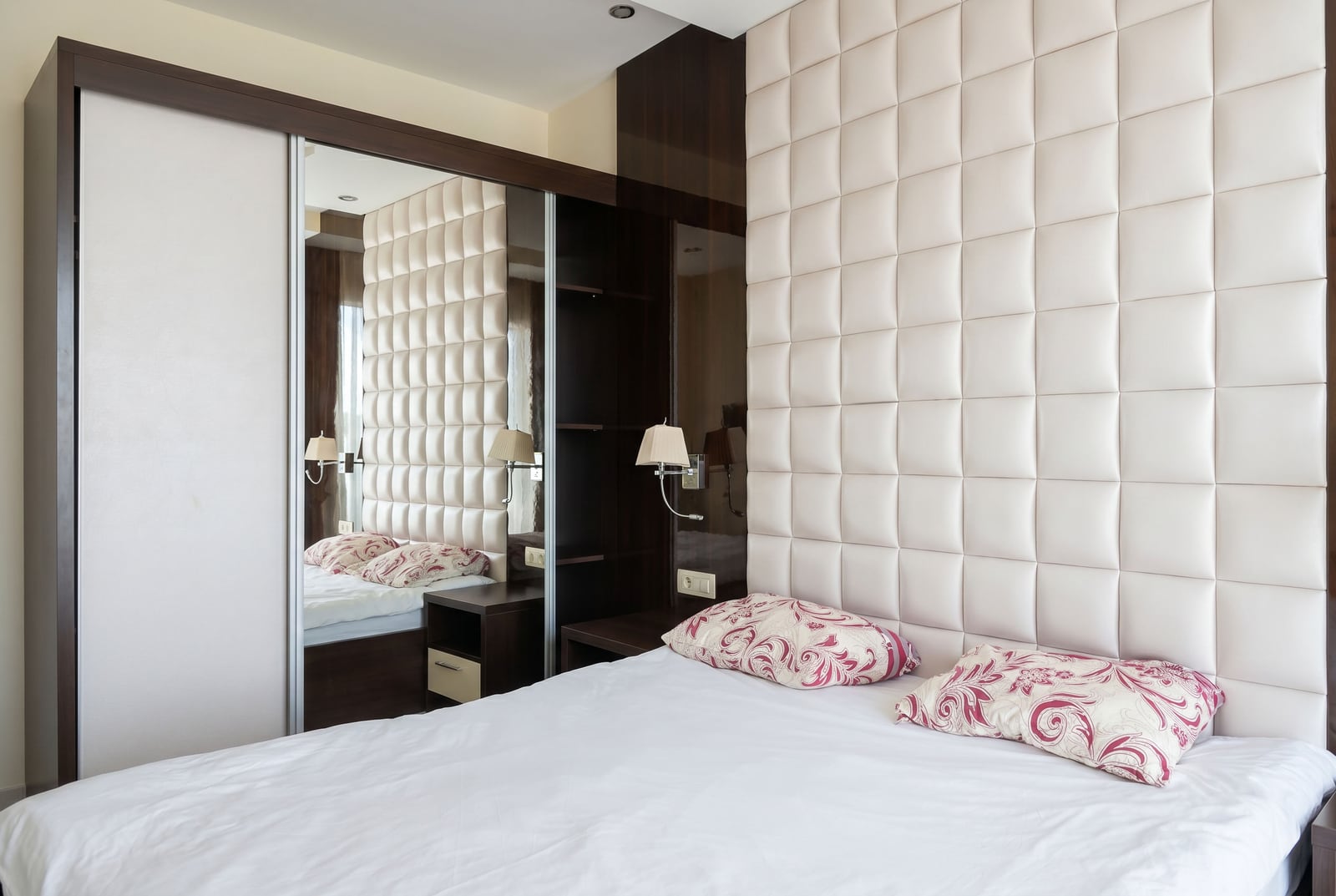 Modern bedroom in an apartment in Bečići, Montenegro: double bed, upholstered headboard, and mirrored sliding-door wardrobe.