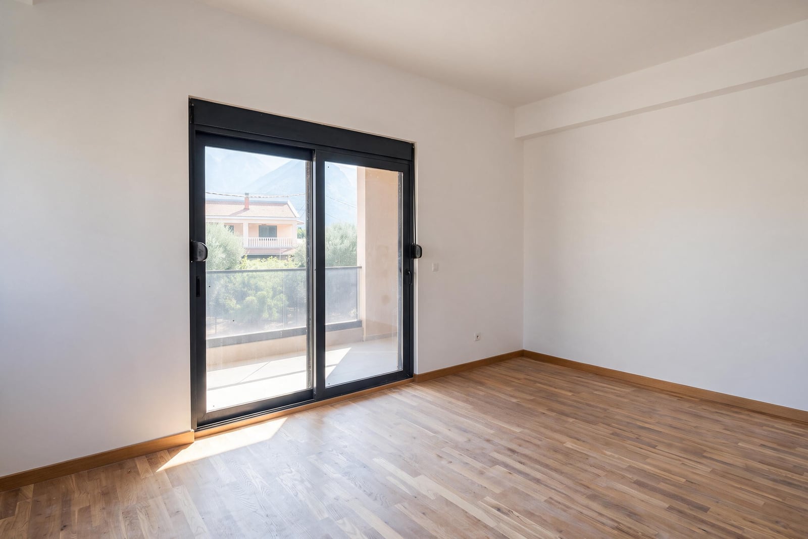 Bright bedroom with parquet flooring, panoramic windows, and access to a balcony in an apartment in Bar, Montenegro.