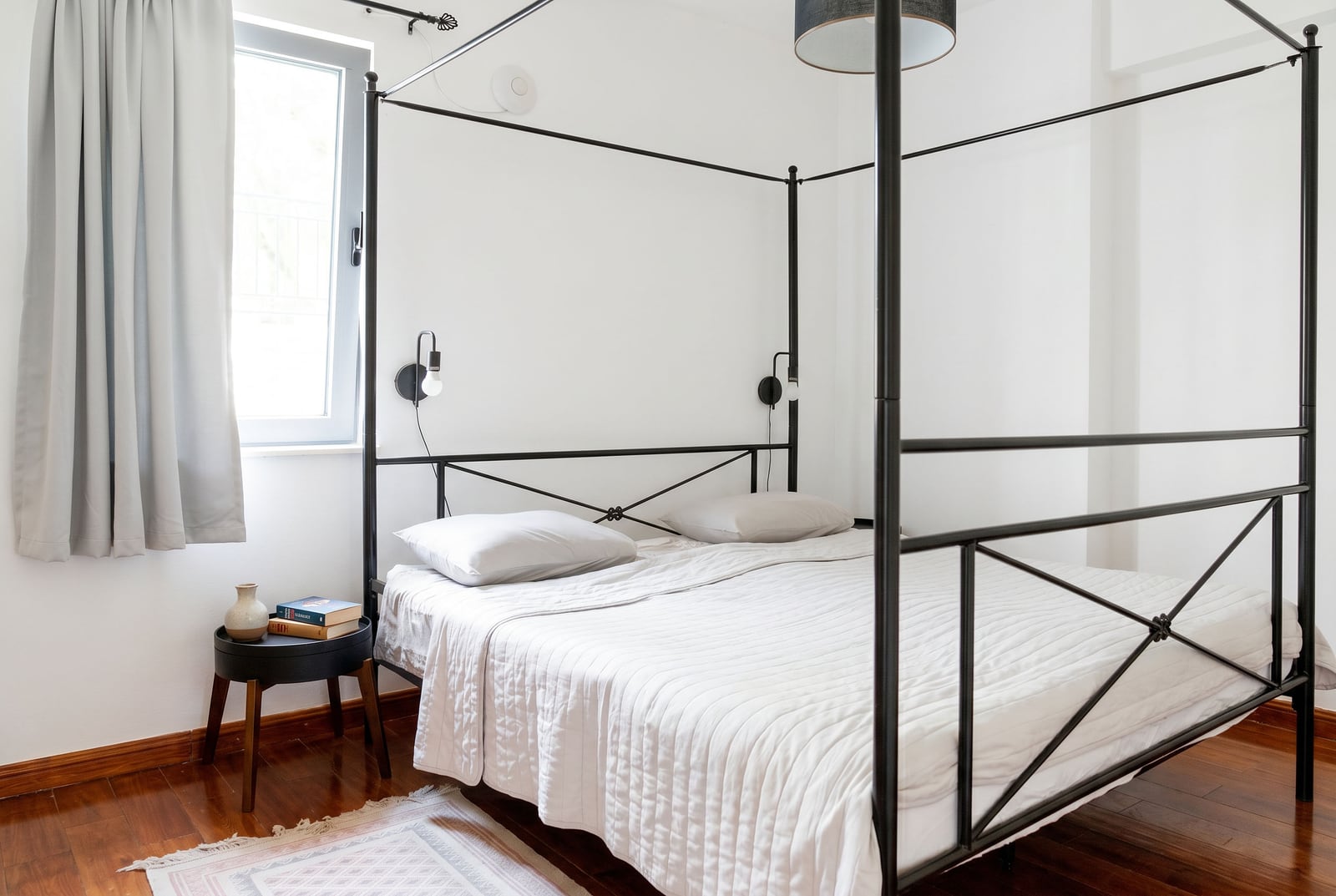 Bedroom with a metal canopy bed in an apartment in Risan, Montenegro: bright interior, parquet flooring.