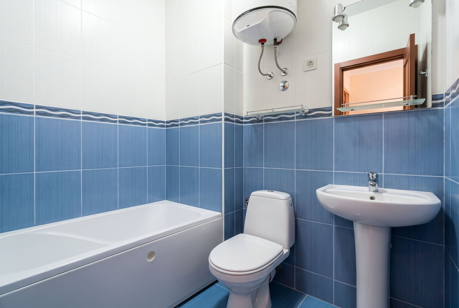 Bathroom in an apartment in Bar, Montenegro: white sanitary ware, blue tiles, and a water heater.