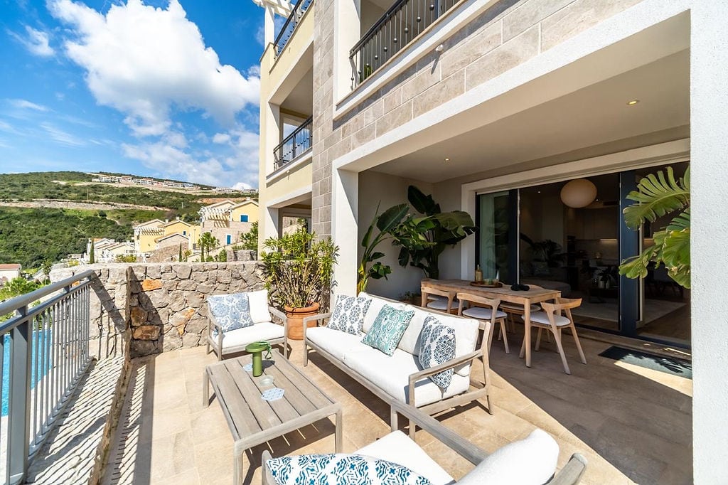 Spacious terrace with furniture and mountain views in the Luštica residential complex, Montenegro. Modern stone finish.
