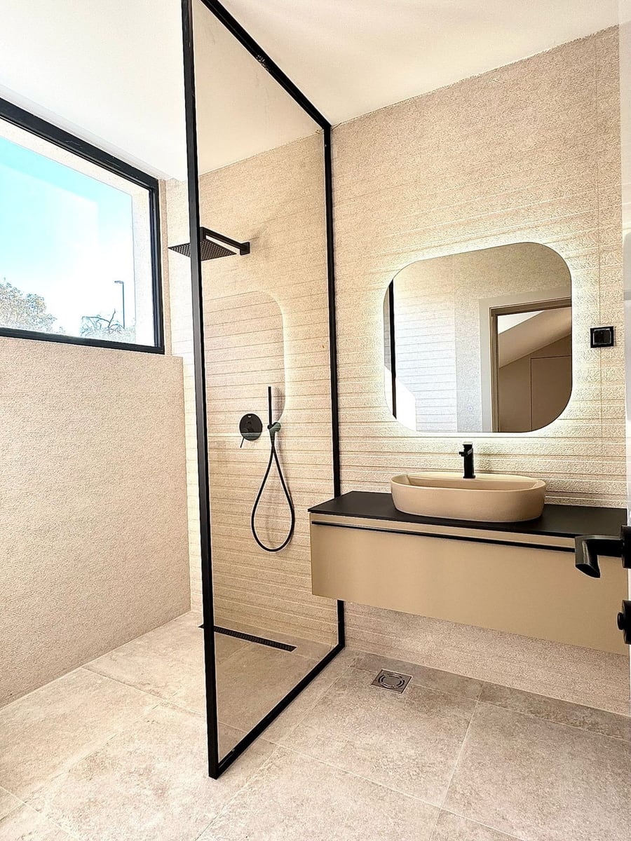 Modern bathroom in a villa in Kamenovo, Montenegro: shower with black profile, countertop sink, and mirror.