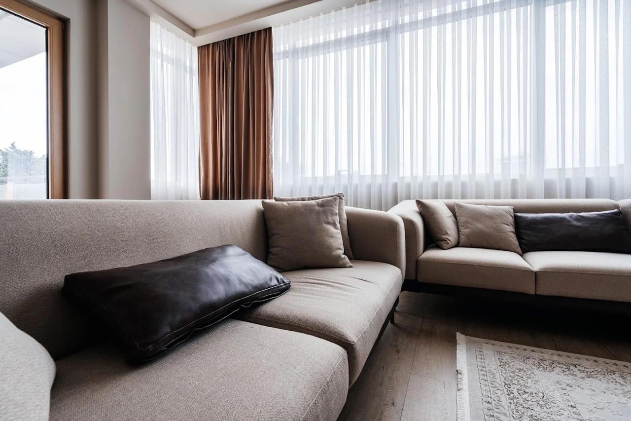 Modern living room with a beige sofa and panoramic windows in an apartment in Budva, Montenegro.