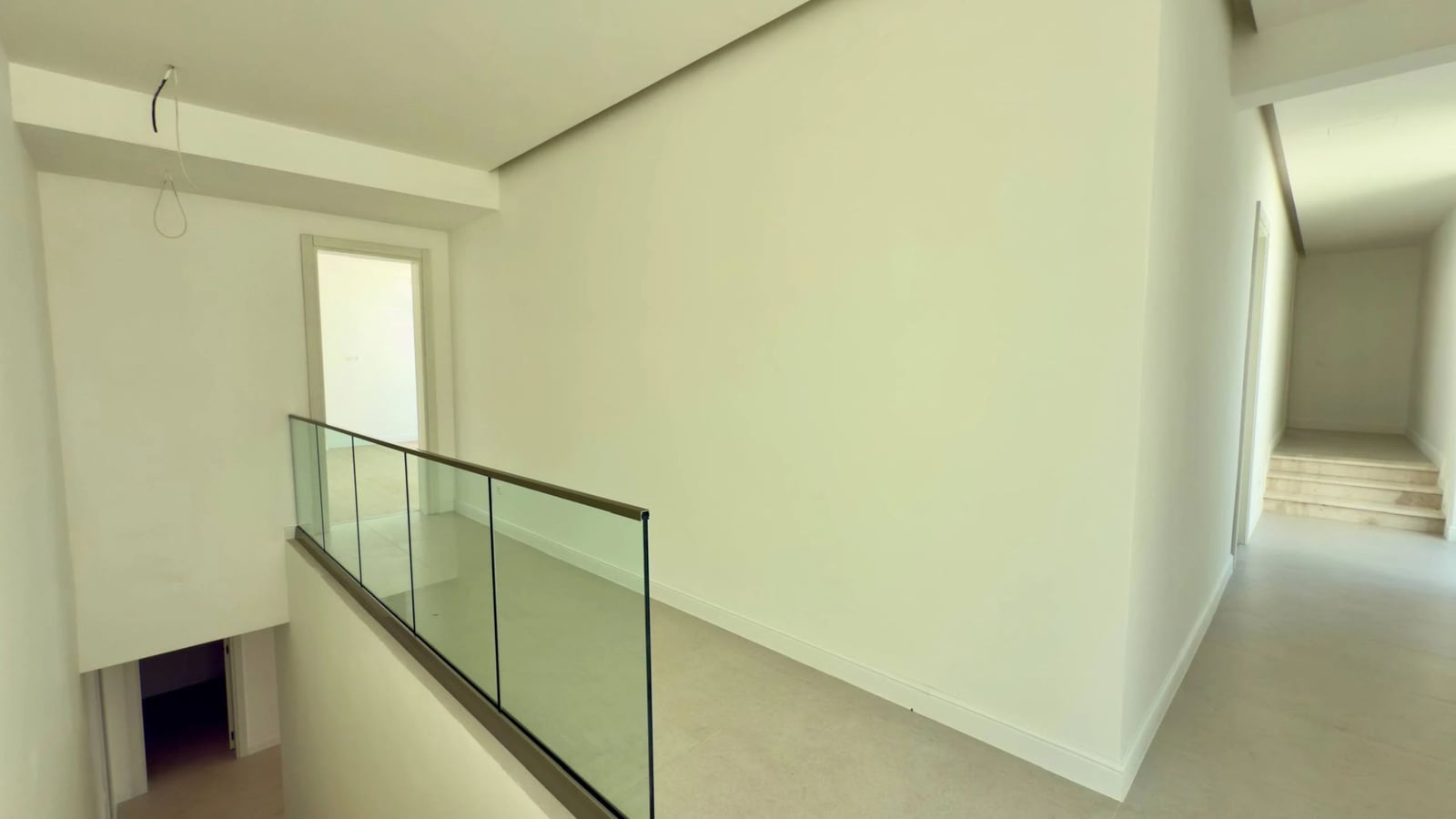 Bright hallway with a staircase and glass railing in a villa in Krašići, Montenegro. Modern interior finish.