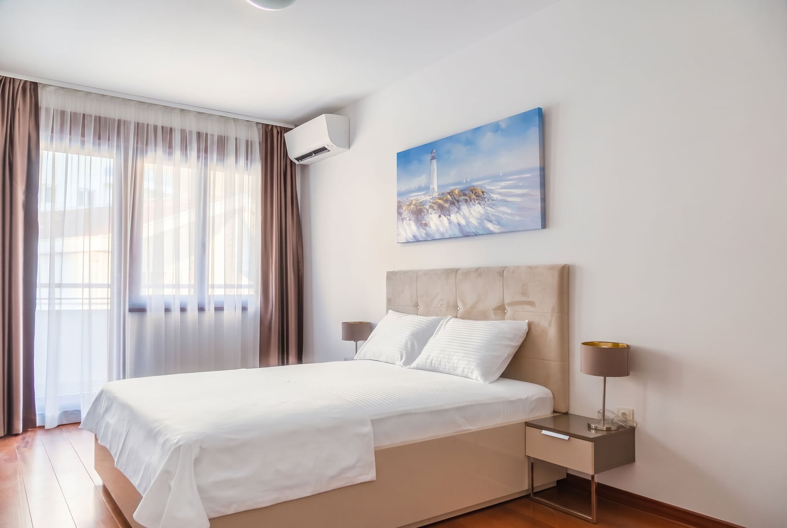 Modern bedroom with a double bed in an apartment, Becici, Montenegro: bright interior, air conditioning, and a balcony.