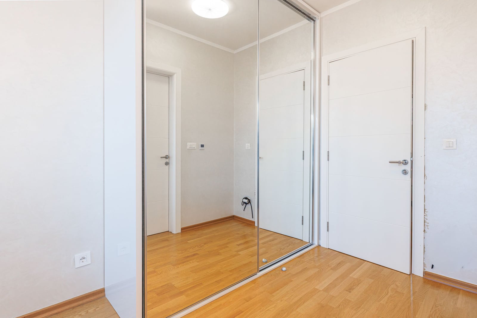 Bright hallway with a mirrored sliding-door wardrobe and parquet flooring in an apartment, penthouse in Bečići, Montenegro.