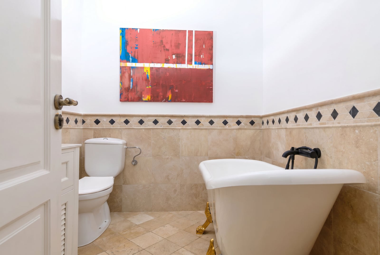 Bathroom in a penthouse in Risan, Montenegro: freestanding bathtub with gold legs and beige tiles.
