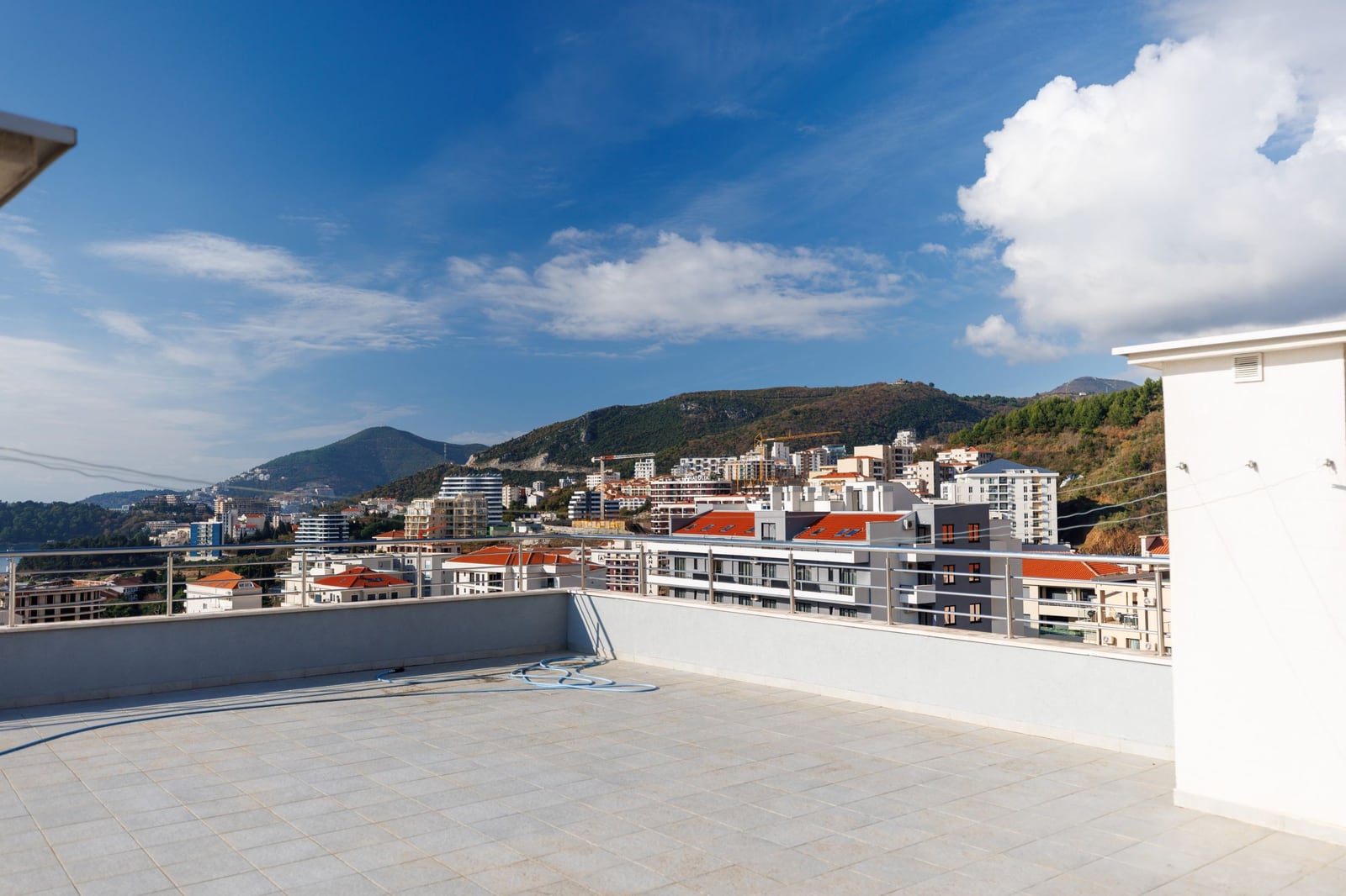 Open penthouse terrace in Bečići, Montenegro, with a panoramic view of the mountains and the cityscape.