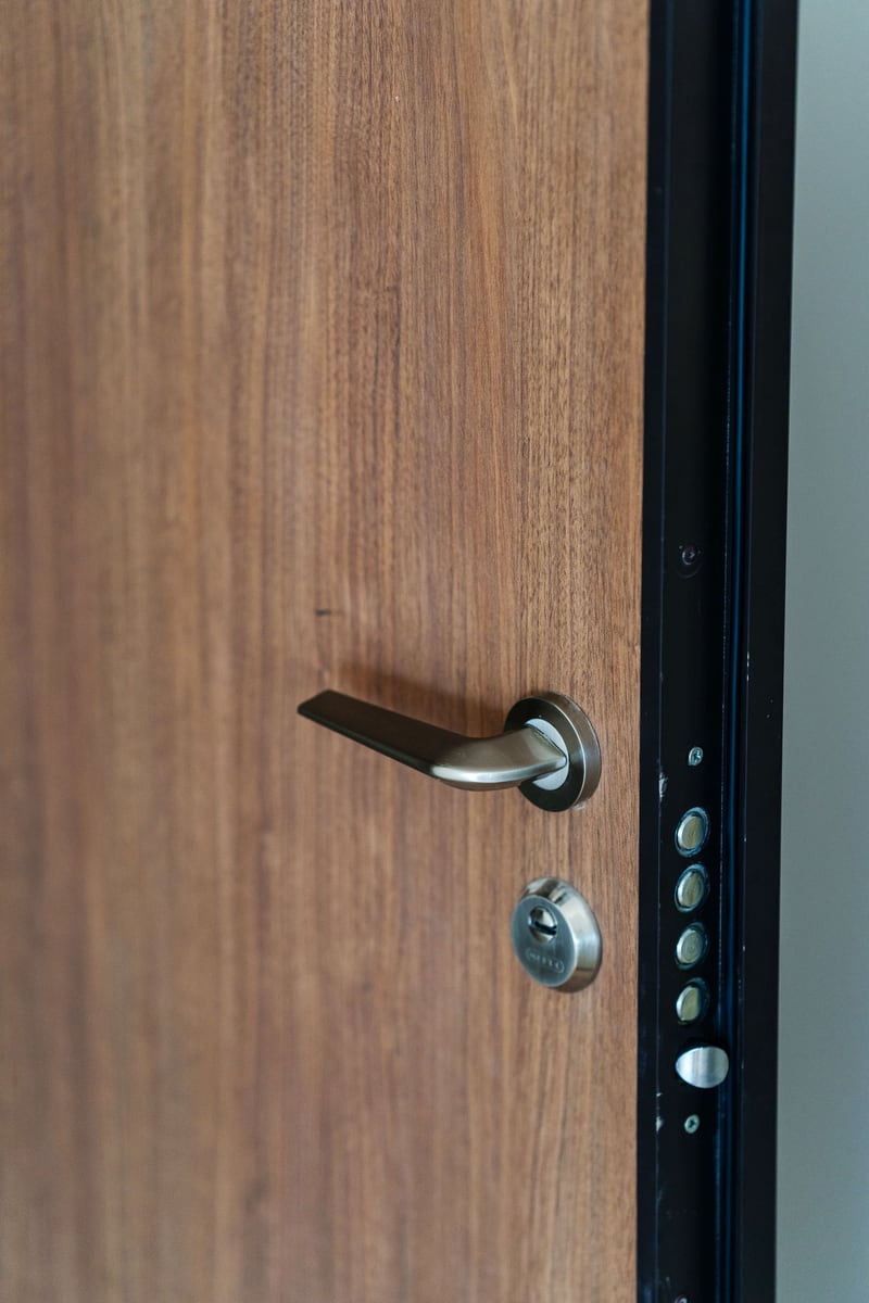 Modern entrance door with wood finish and a secure lock in a residential complex, Budva, Montenegro.