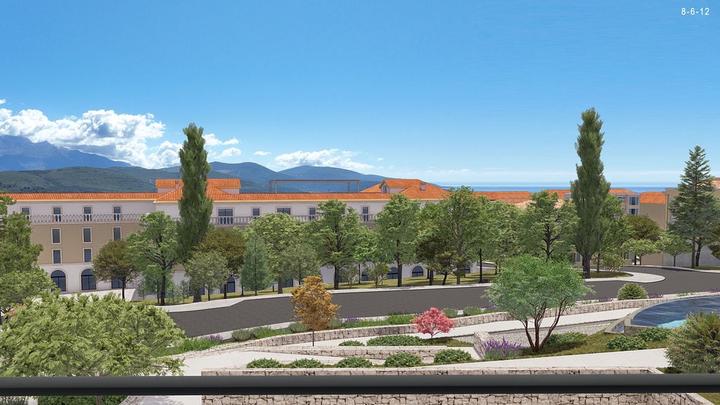 View of a residential complex in Luštica, Montenegro: modern buildings with terracotta roofs, a park, and a sea view.