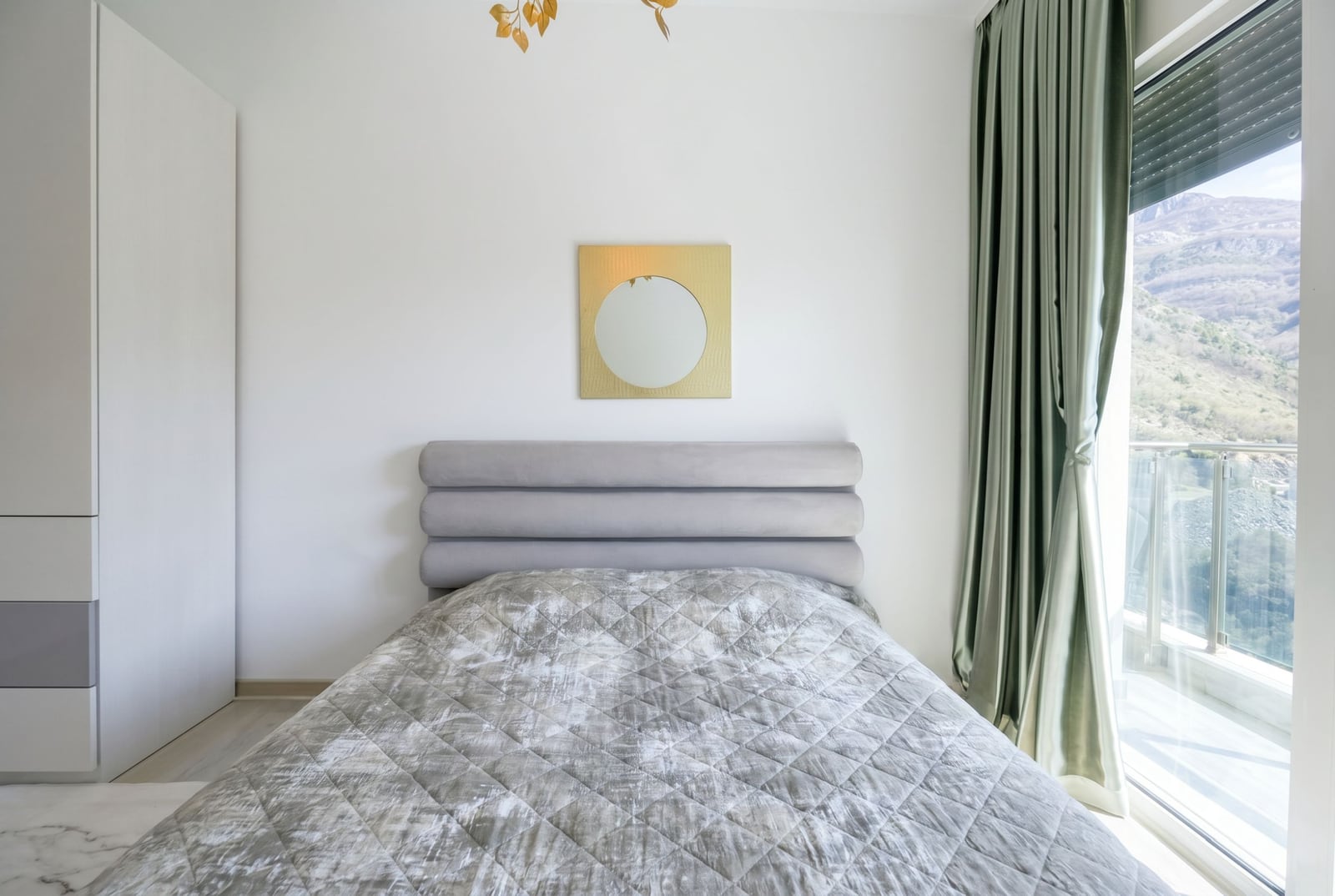 Modern bedroom in an apartment in Bečići, Montenegro: double bed, panoramic window with mountain view.