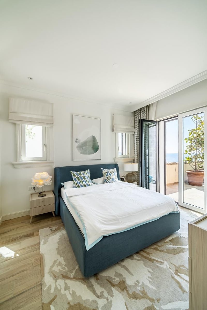 Modern bedroom with a double bed and access to a terrace with a sea view in the Luštica residential complex, Montenegro.