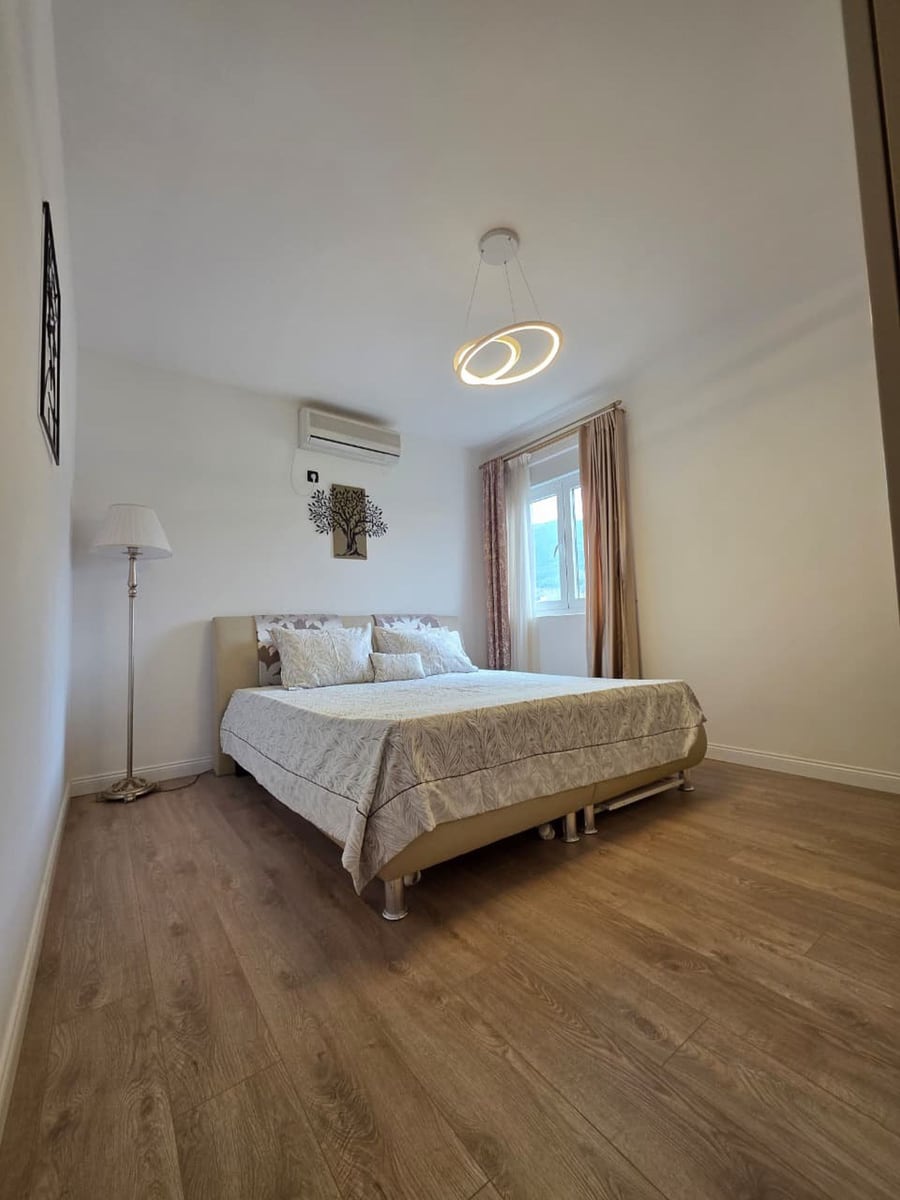 Bright bedroom with a double bed in an apartment in Bečići, Montenegro: laminate flooring, air conditioning, and modern decor.