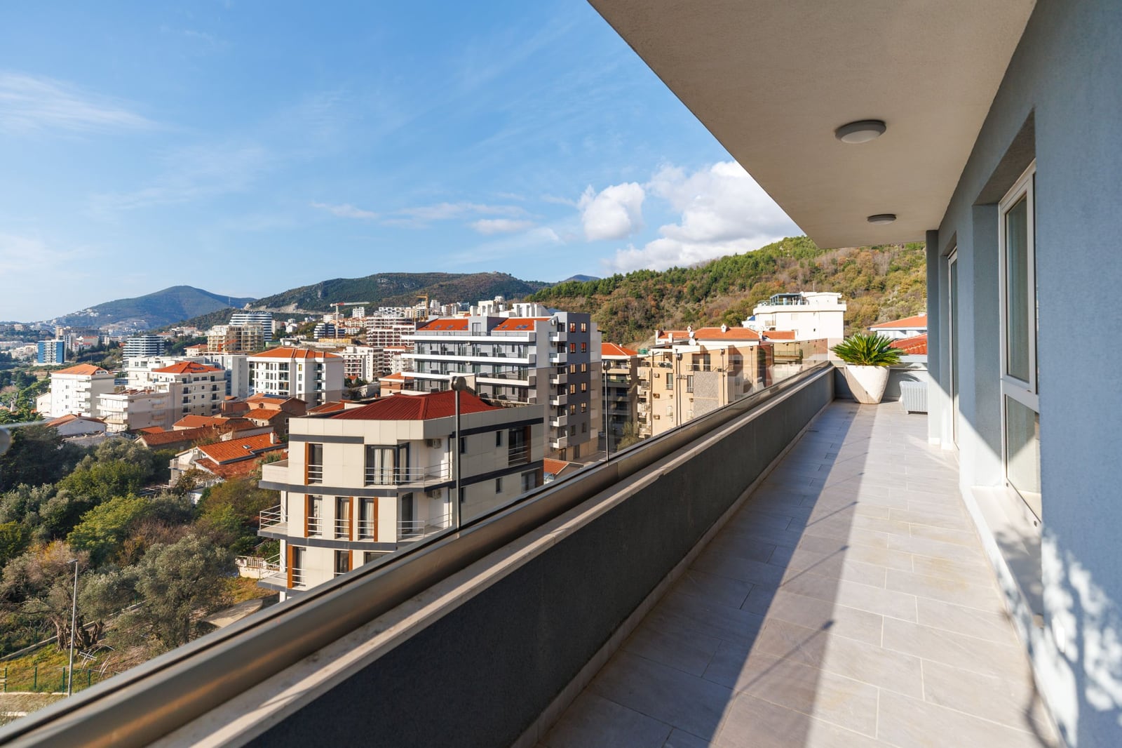 Spacious penthouse balcony in Bečići, Montenegro, with panoramic views of the city, mountains, and modern architecture.