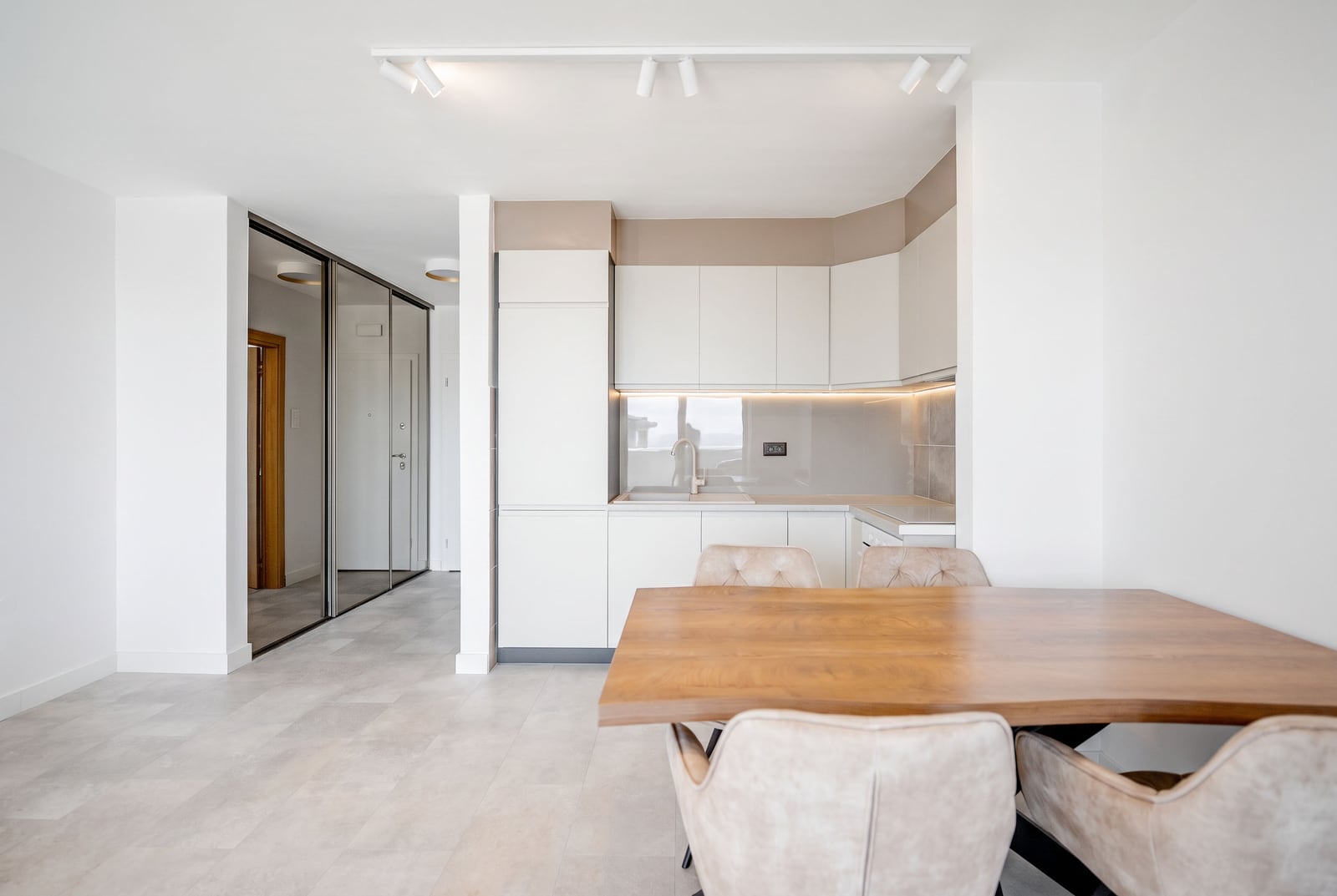 Modern kitchen-living room with white cabinetry and dining table in an apartment in Sveti Stefan, Montenegro.