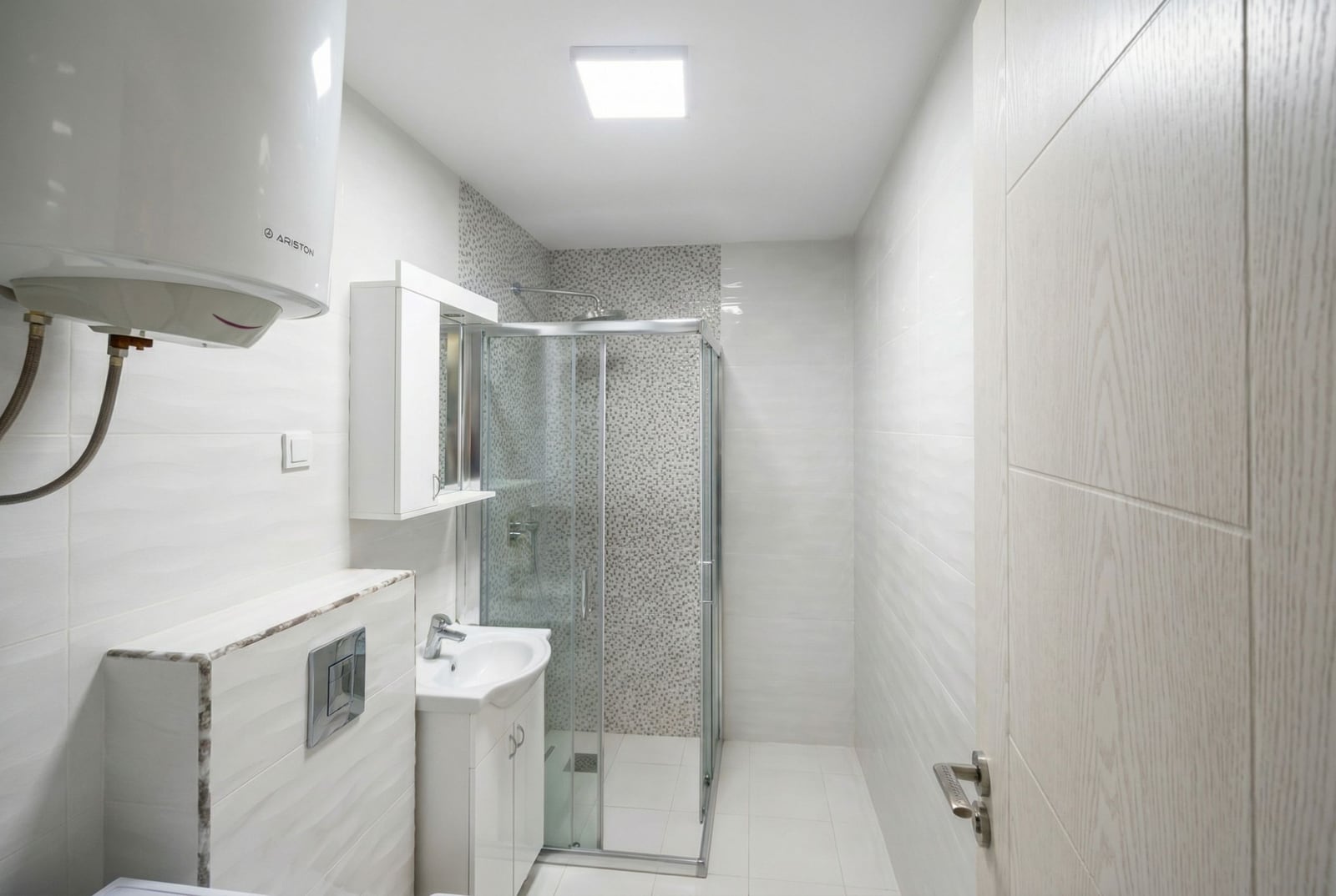 Modern bathroom with a shower cabin in an apartment, Bečići, Montenegro: light tiles and an Ariston water heater.