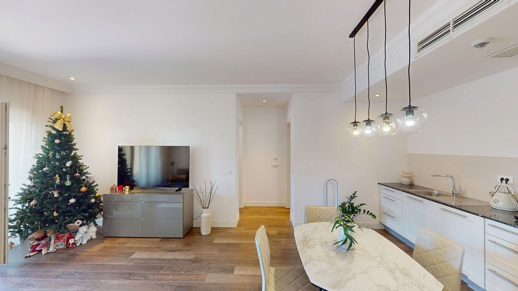 Modern living room with kitchen in an apartment, Luštica, Montenegro: bright interior, dining area, and Christmas tree.