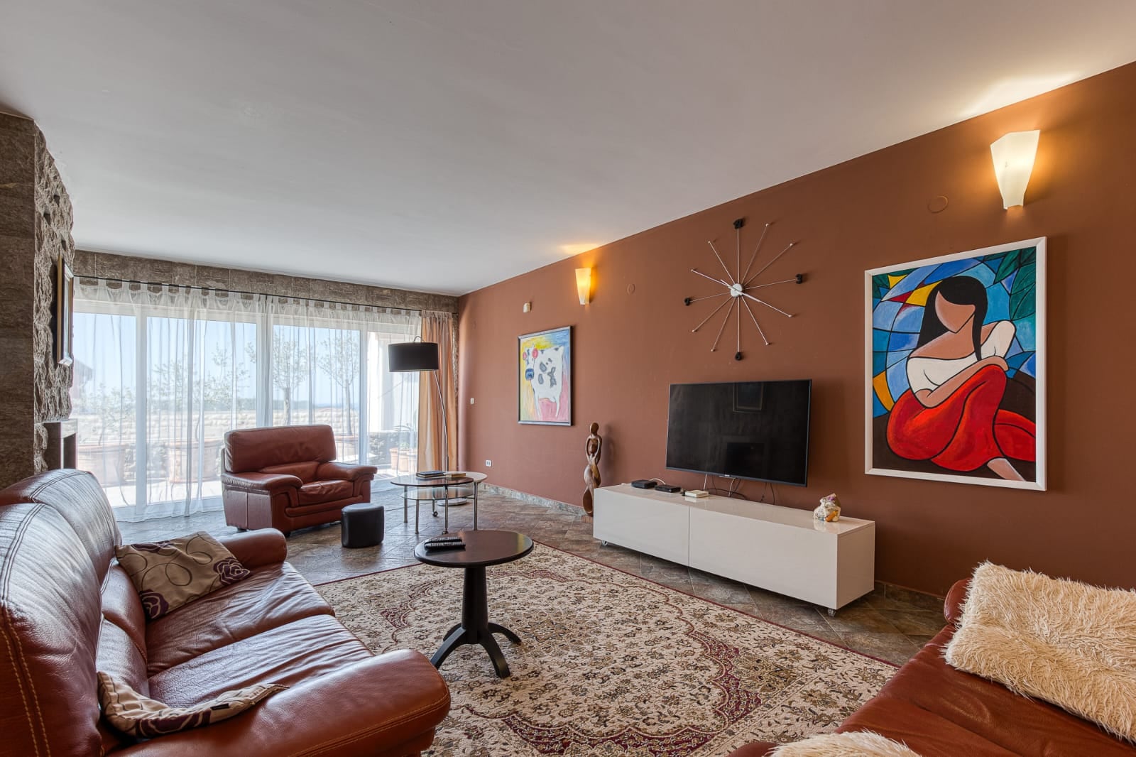 Living room of a villa in Bečići, Montenegro: leather furniture, panoramic windows, stone finishes, and modern-style decor.