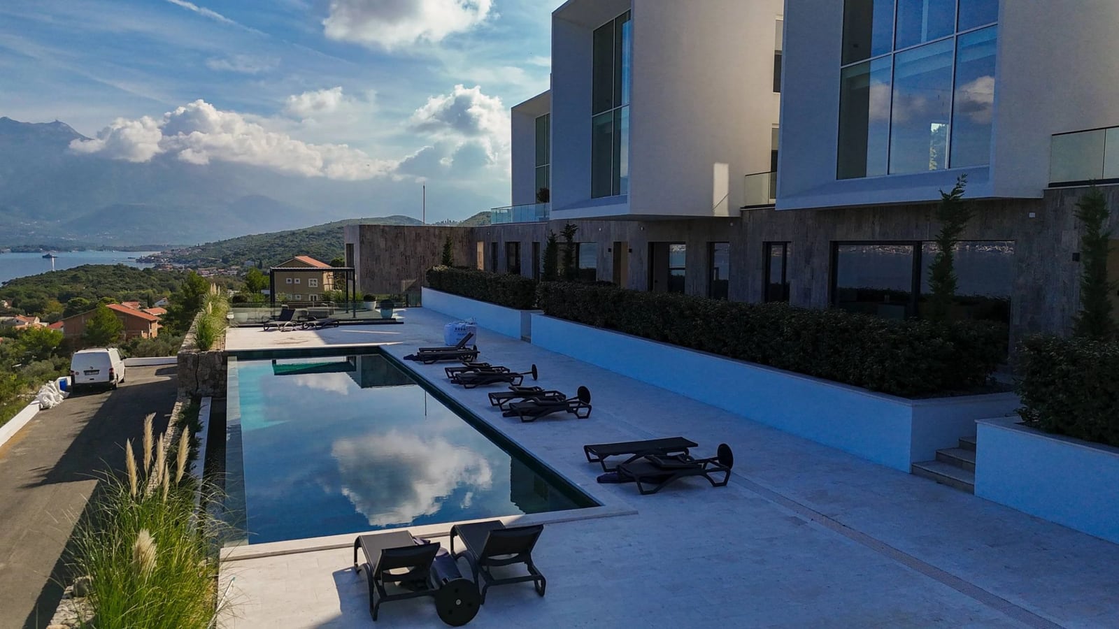 Modern villa with a pool and sea view in Krašići, Montenegro: terrace with sun loungers and panoramic scenery.