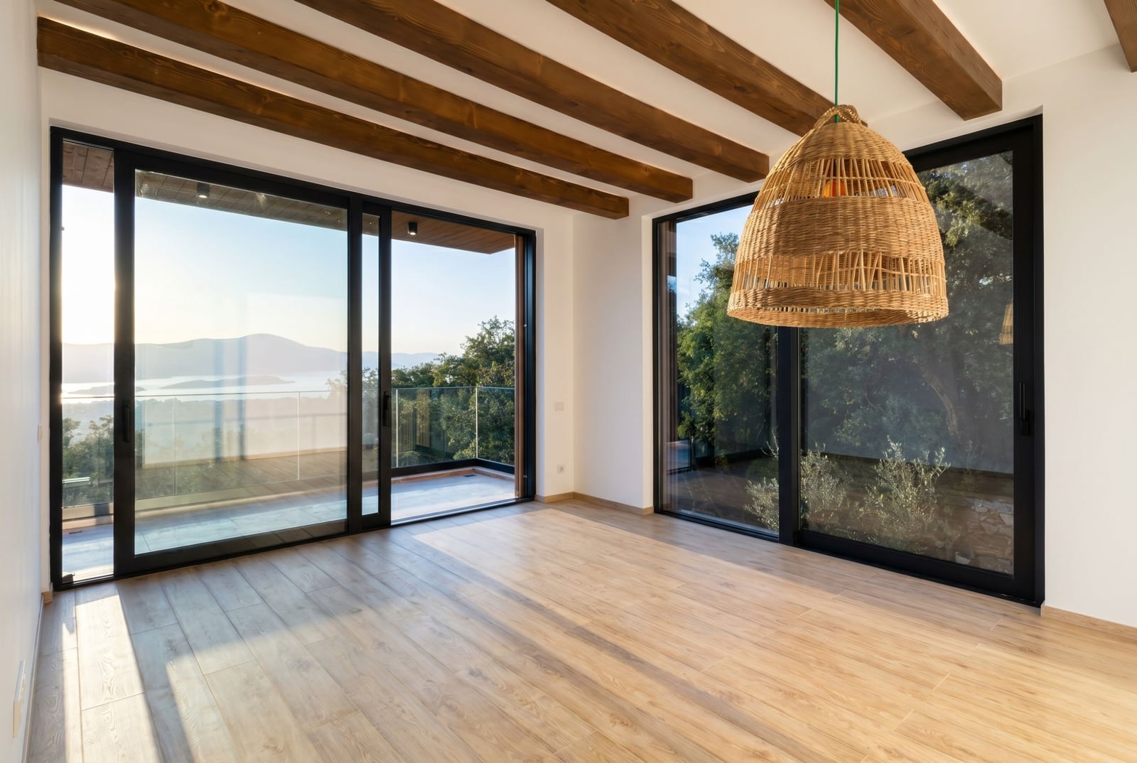 Villa living room in Kavac, Montenegro: panoramic windows, wooden ceiling beams, sea view, and a woven pendant light.