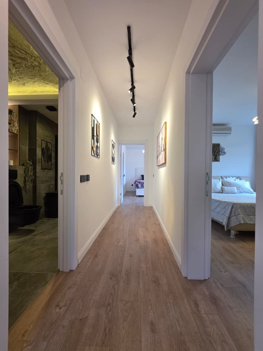 Modern hallway in an apartment in Bečići, Montenegro: bright interior, track lighting, and a view of the bedroom and bathroom.