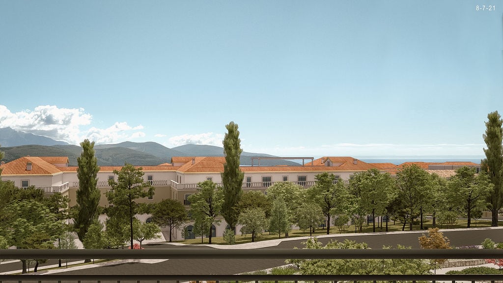View of a modern residential complex with tiled roofs and a green garden in Luštica, Montenegro.