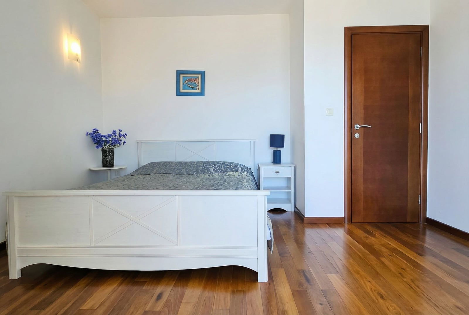 Bright bedroom with white furniture and parquet flooring in an apartment for sale in Tivat, Montenegro.