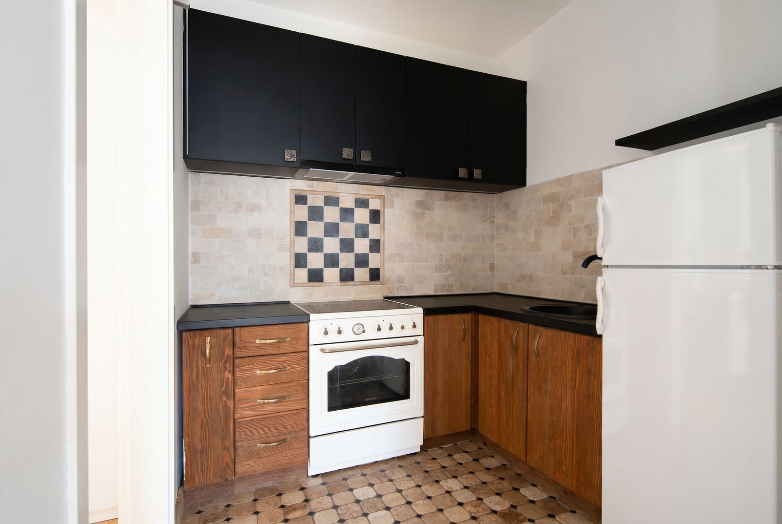 Kitchen in an apartment in Risan, Montenegro: combined kitchen unit, white stove, stone wall finish, and tiled floor.